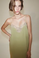 Vestido midi confeccionado en hilatura de viscosa, de color verde con detalles de encaje a contraste en el escote y el bajo. Cuenta con escote recto y tirantes finos ajustables.