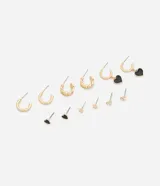 Kit de aros metálicos dorados con seis pares variados, que incluye aros argollas lisas, aros con textura de cadena, aros con dijes colgantes de corazón esmaltado en negro, y pequeños aros abridores con detalles de estrella y piedras de strass.