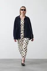 Vestido midi blanco con estampado de lunares negros, de silueta fluida con cuerpo fruncido, escote recto y tiras finas regulables. Presenta un corte bajo el busto que genera una caída suelta y liviana.