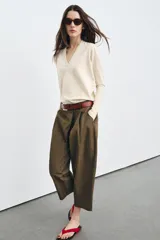 Pantalón cropped de tiro medio con diseño de pinzas en el delantero, bolsillos laterales y bolsillos de vivo en la parte trasera. Cuenta con trabillas en la cintura y cierre frontal con cremallera y botón.