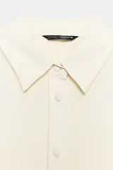 Camisa de manga larga color celeste claro, con cuello solapa y cierre frontal de botones.