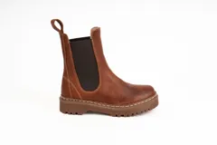 Bota de caña baja tipo chelsea de cuero encerado color terracota, con elásticos negros en los laterales, costuras visibles y suela track marrón con plataforma dentada.