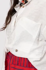 Camisa amplia blanca con bolsillos frontales gigantes y cierre frontal con botones.