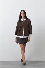 Saco tipo capa de punto, color marrón, con diseño minimalista, caída fluida y cierre frontal con botones metálicos.