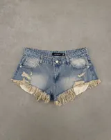 Short de denim celeste tiro bajo, con roturas y flecos largos deshilachados en el ruedo, y bolsillos internos asomando.