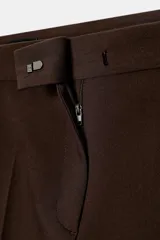 Pantalón de vestir color marrón oscuro, tiro alto, corte recto o ligeramente cropped, con pinzas frontales y bolsillos laterales.
