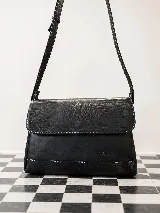 Cartera de hombro Sagali modelo Pianosa, confeccionada 100% en cuero vacuno negro con detalles texturizados símil reptil en la solapa y base, y costuras en contraste. Cuenta con correa ajustable.