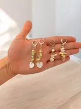 Par de aros colgantes con argollas tipo huggie de metal plateado. El diseño presenta una tira de piedras naturales irregulares en tonos verdes o crudos, finalizando en un dije de corazón de nácar o piedra clara.