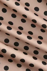 Vestido midi de satén color beige con estampado de lunares negros, breteles finos ajustables, escote recto con ribete de encaje negro, tajo lateral con detalle de encaje y bajo con terminación de encaje.