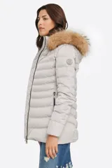 Campera puffer color beige con relleno de plumón, cierre central con cremallera de doble carro, bolsillos laterales y capucha desmontable con borde de piel sintética marrón. Largo 70cm.