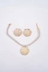 Set compuesto por un collar de cordón trenzado negro con dije central en forma de concha dorada y un par de aros a juego con diseño de concha dorada.