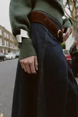 Sweater de punto color verde militar, con cuello asimétrico y manga larga con brazalete metálico en el puño.