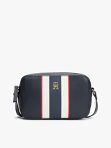 Cartera tipo bandolera de Tommy Hilfiger, confeccionada en poliuretano color azul marino. Presenta un diseño rectangular con una franja vertical central en colores blanco, azul y rojo, y el logo monograma TH en metal dorado en el frente. Incluye correa ajustable y cierre superior.