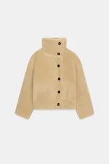 Cazadora reversible de cuello subido y manga larga, con bolsillos de vivo en el delantero y cierre frontal con botones. Confeccionada en tejido combinado con efecto pelo y efecto ante.