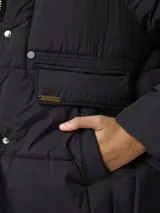Campera puffer de nylon color negro, con cuello alto, cierre frontal con cremallera y botones a presión. Presenta bolsillos frontales con solapa y diseño acolchado.