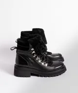 Borcegos de cuero vacuno en tonos marrón, con diseño de caña media y cuello con forro de piel sintética negra. Presentan cordones marrones, ganchos metálicos para ajuste y suela de goma tipo track con plataforma.