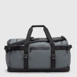Bolso tipo duffel de diseño versátil en color gris con detalles en negro. Cuenta con compartimento principal amplio, bolsillos exteriores con cierre, asas de mano y correas ajustables para llevar como mochila.