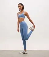 Legging deportiva de tiro alto color azul, confeccionada en poliamida con elastano. Presenta un diseño ajustado al cuerpo con bies contrastante en color blanco en la cintura y bolsillo integrado.