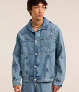 Campera masculina de jeans celeste, modelo trucker boxy vintage con cuello inglés, manga larga con puños abotonados, abotonado delantero, bolsillos delanteros y recortes.