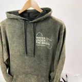 Canguro verde oliva con efecto lavado, corte oversize, capucha con cordón ajustable y bolsillo tipo canguro. Estampado frontal con texto en blanco "Water under the bridge" y logo de la marca Duxon.