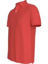 Chomba color coral de Tommy Hilfiger, modelo 1985, de corte regular, con cuello tipo chomba, cartera de dos botones, logo de Tommy Hilfiger bordado en el pecho y diseño de rayas en el interior del cuello. Confeccionada en mezcla de algodón y poliéster.