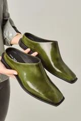 Zuecos color verde oliva de cuero vacuno, con punta cuadrada y suela plana.