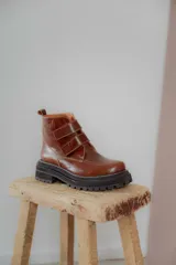 Borcego de cuero color suela con puntera redondeada, cierre mediante tiras de velcro y suela track de goma negra.
