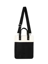 Matera vertical de diseño bicolor, con cuerpo inferior en cuero sintético negro y sección superior en tejido texturizado color crema. Incluye asas cortas de mano y una correa larga ajustable con logo grabado, ambas en color negro.