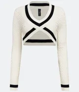 Suéter cropped de punto texturizado color crema, con escote en V y detalles a contraste en negro en mangas, cuello y busto.