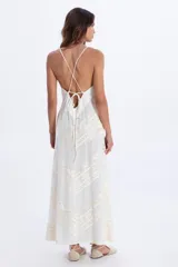 Vestido largo fluido color blanco con tirantes finos, escote en V y bordado con hilo dorado en diseño triangular geométrico.