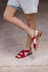 Sandalia negra con tiras cruzadas de neopreno y plantilla de cuero, con taco bajo cuadrado y punta abierta.