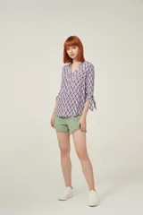 Blusa de viscosa con estampado geométrico en tonos violeta y beige. Tiene cuello mao, botones frontales y mangas 3/4 con lazo en los puños.