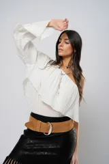 Blusa blanca con un hombro descubierto, manga larga con volados y textura arrugada.