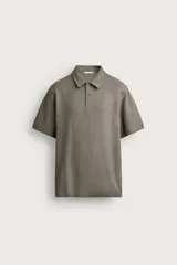 Remera polo regular fit de color gris oscuro, confeccionada en tejido de algodón con textura de rayas verticales. Cuenta con cuello solapa, cierre frontal con botones y mangas cortas con terminación en rib.