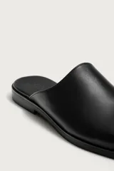 Zueco de vestir para hombre confeccionado en piel de color negro, con horma redonda, diseño destalonado y suela plana a tono.