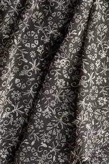 Vestido corto de gasa transparente en color negro con estampado floreado. Presenta escote halter alto, espalda abierta, elástico fruncido en la cintura y falda escalonada con vuelo. Incluye forro interior.