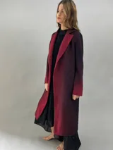 Tapado de paño de lana con diseño de solapas amplias, corte recto y bolsillos laterales ocultos. Presenta un degradado de color que va desde un tono bordó intenso en las solapas y puños hacia un tono más oscuro en el cuerpo.