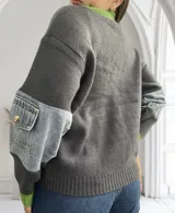 Sweater gris con cuello y puños verdes, mangas largas con apliques de denim y bolsillo con botón.