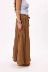 Falda larga marrón de lino y viscosa, con cintura elastizada y cordón ajustable. Tiene bolsillos laterales y corte amplio.