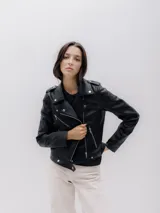 Chaqueta biker negra de cuero sintético con cuello de motociclista, mangas largas, cierre con cremallera y bolsillos delanteros.