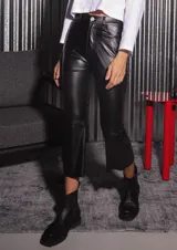 Pantalón de tela engomada color negro, con corte capri semi oxford, tiro medio-alto, cierre frontal con botón metálico y bolsillos traseros.