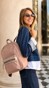 Mochila de nailon color rosado, con bolsillo frontal con cierre y detalles en símil cuero. Cuenta con amplia capacidad interior, asas de mano, correas regulables y un bolsillo trasero vertical.