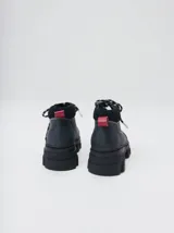 Bota acordonada de estilo montañés con suela track de goma robusta. Confeccionada en cuero con detalles de gamuza en la talonera y tirador trasero. Presenta costuras a contratono y cordones bicolores.