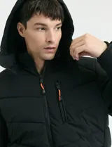 Campera capitoneada de poliéster color negro, con capucha desmontable, cierre frontal y bolsillo en el pecho con cierres engomados y tiradores en color naranja.