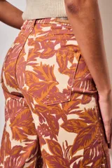 Jean wide leg de tiro medio, con estampado botánico en tonos terracota y beige, confeccionado en denim de algodón con elastano.