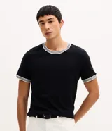 Remera regular de manga corta y cuello redondo color negro, con diseño texturizado y detalles de rayas contrastantes en cuello y puños.