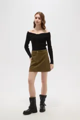 Falda mini de corte recto confeccionada en pana de algodón color verde oliva, con cierre frontal de botón metálico y pasacintos.