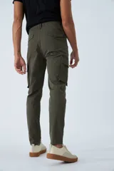Pantalón cargo de corte slim, color verde militar, con cierre frontal, botón en la cintura, pasacintos y bolsillos laterales con solapa y botones.