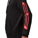 Canguro con capucha Nike Jordan, confeccionado en tejido técnico negro con detalles en color rojo vibrante. Presenta el logo Jumpman en el centro del pecho y franjas laterales en las mangas. Incluye bolsillo frontal tipo canguro y cordones ajustables en la capucha.