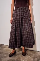 Pantalón de corte wide leg con diseño de cuadros, tiro medio y pinzas frontales que aportan volumen y movimiento a la prenda.